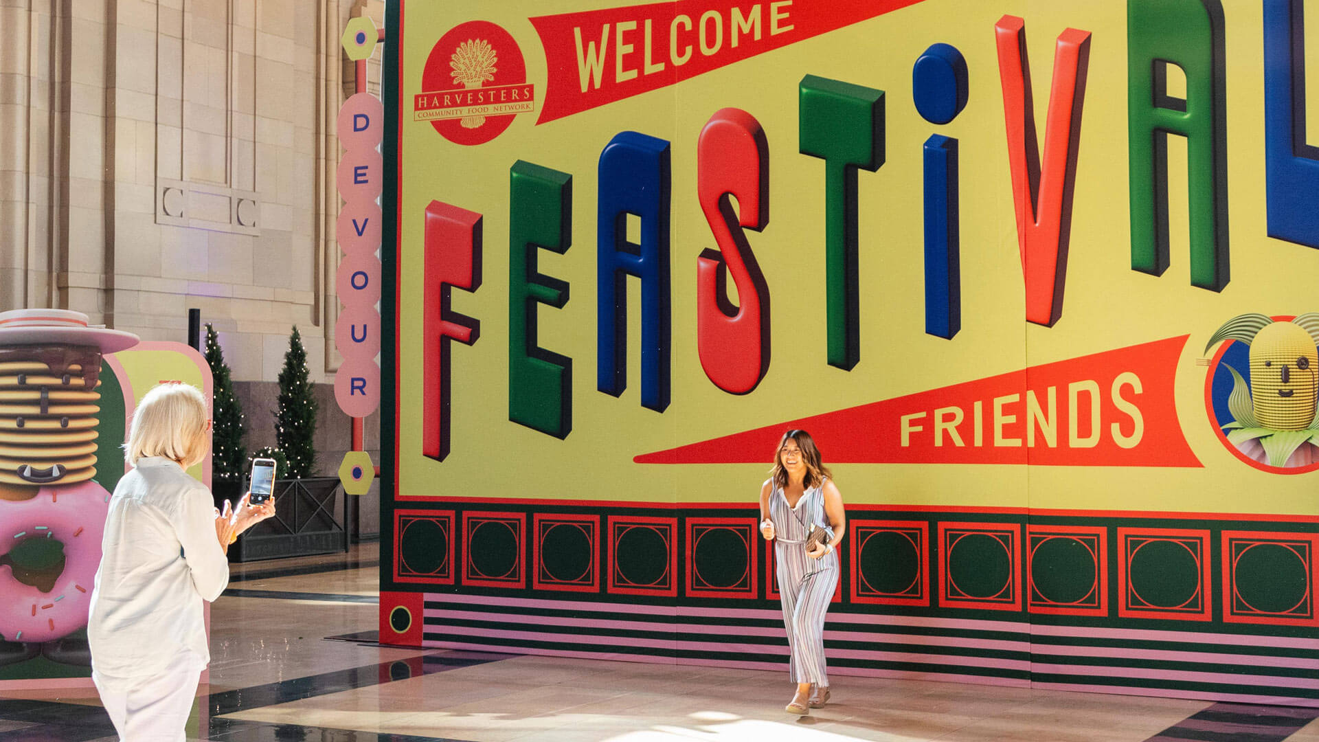 Woman laughing while getting her photo taken in front of giant Welcome Feastival Friends sign at the event.
