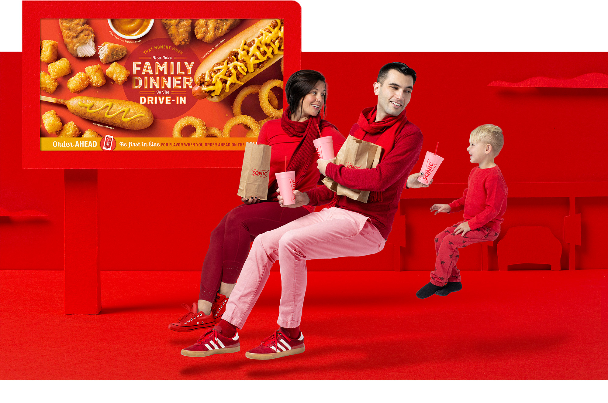 Family in front of signage at stylized SONIC drive-in that says: That Moment You Take Family Dinner to the Drive-In