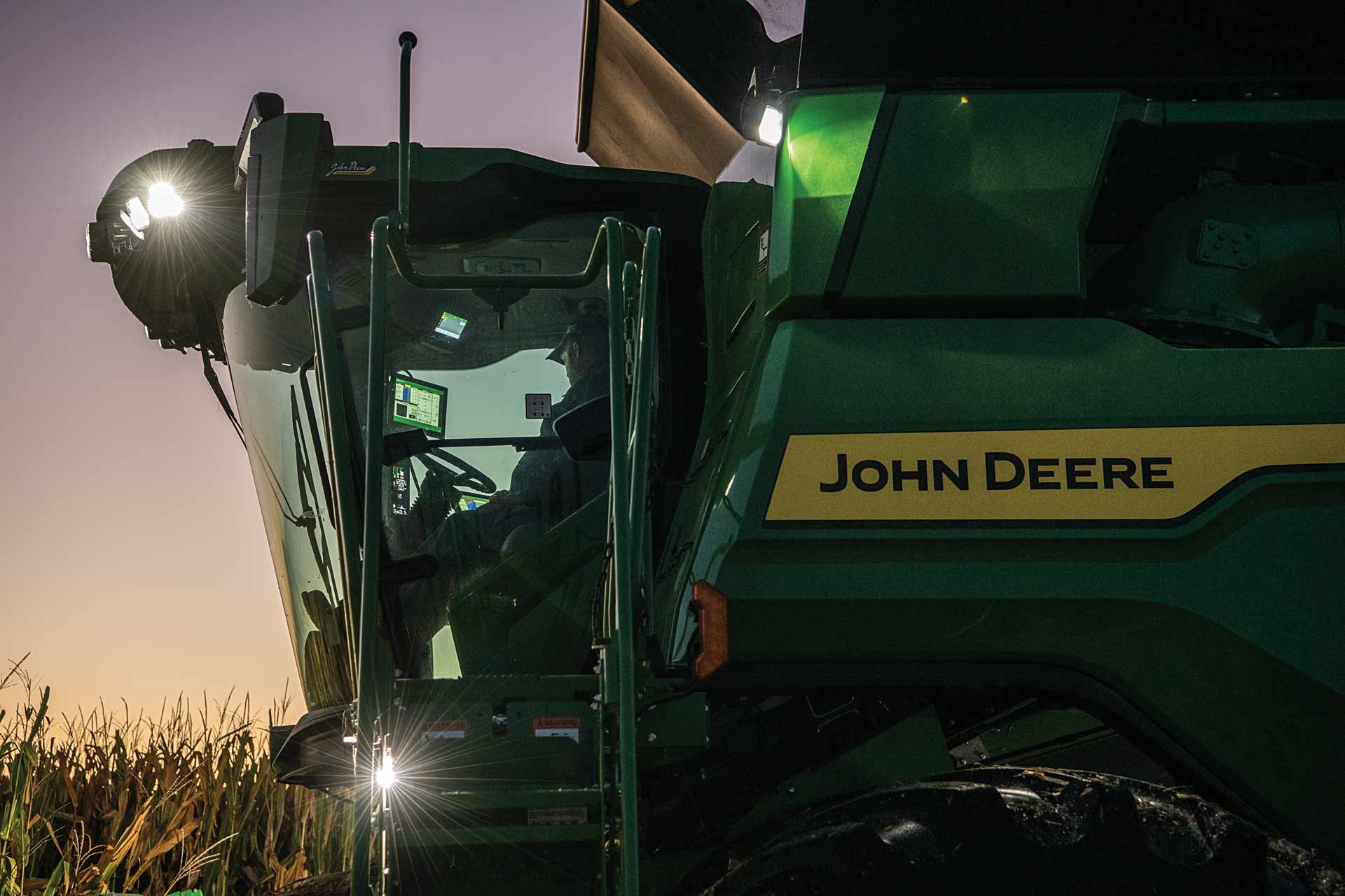 Close up of John Deere combine cab with a silhouetted person inside