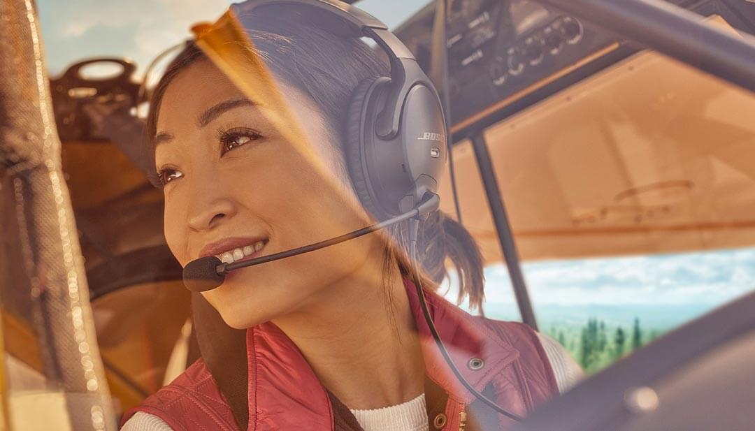 Woman in plane cockpit looking out the window while wearing Bose Aviation A30 headset.