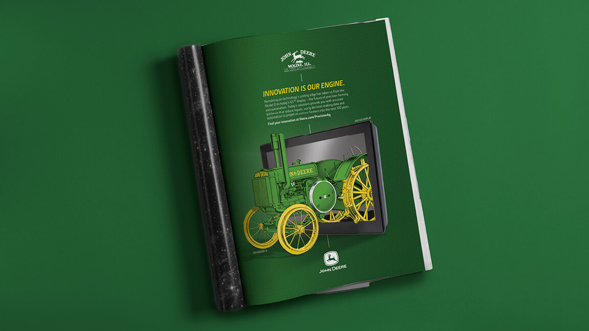John Deere Model D print ad with the headline "Innovation is Our Engine" and an image of a Model D tractor emerging from a monitor screen.