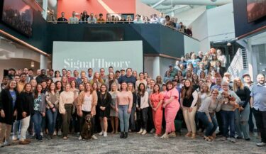 Large group photo of Signal Theory employees in the Kansas City office atrium.